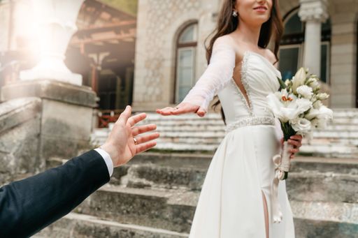 The bride and groom posing together on the stairs of a castle