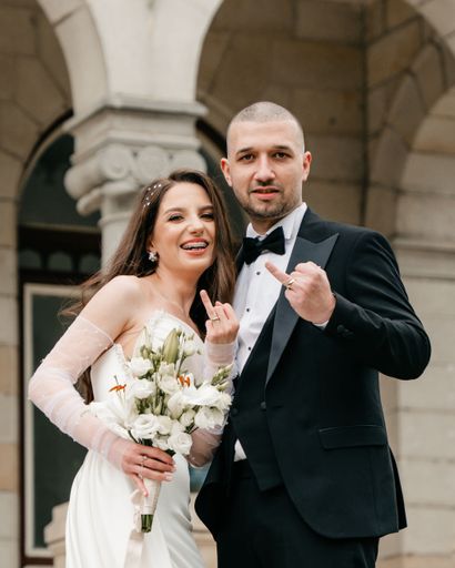 The bride and groom posing together on the stairs of a castle