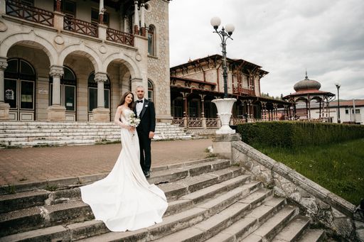 The bride and groom posing together on the stairs of a castle