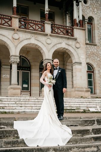The bride and groom posing together on the stairs of a castle