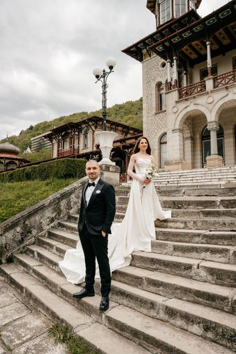 The bride and groom posing together on the stairs of a castle