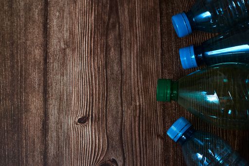 An overhead closeup shot of blue and green plastic bottles on a wooden background