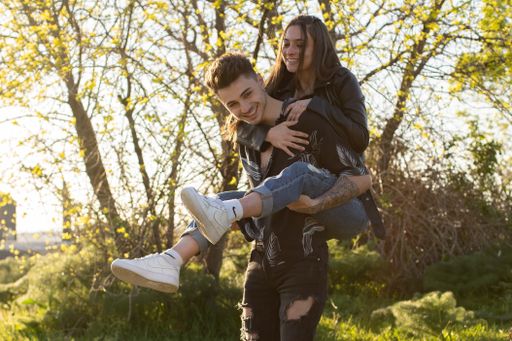 A beautiful shot of a woman riding on her partner's back having fun in the field