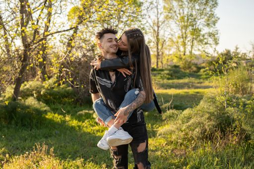 A beautiful shot of a woman riding on her partner's back having fun in the field