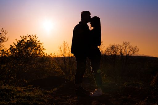 A scenic shot of a silhouette of a couple kissing during the sunset