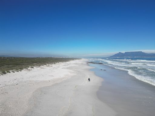A scenic view of a sandy beach against the sea with the view of Table Mountain in South Africa