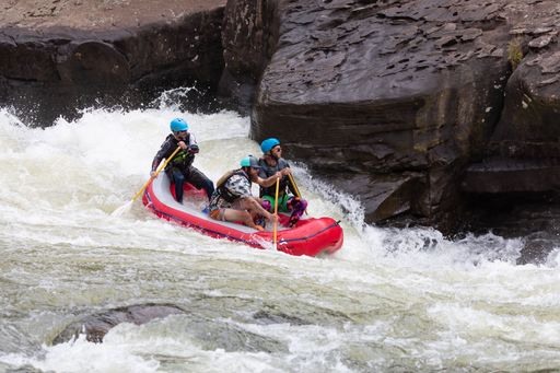 The people in an inflatable boat riding a rushing river's wave. Rafting in Fayetteville, West Virginia.