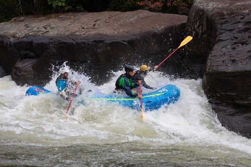 The people in an inflatable boat riding a rushing river's wave. Rafting in Fayetteville, West Virginia.