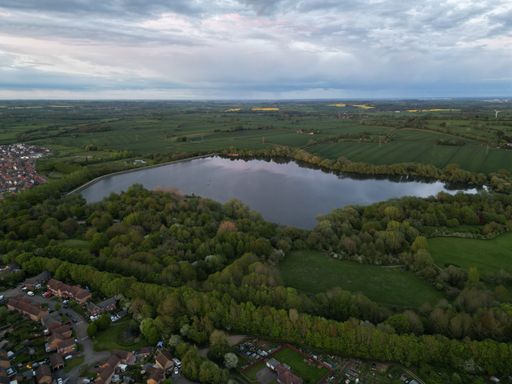 An aerial view of a tranquil lake surrounded by an expanse of lush green grass