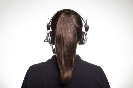 A closeup of Brazilian female wearing a headphone around her ponytailed hair on a white background