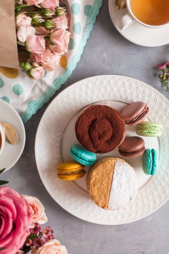 A top view of tasty sweets on the table served with tea and arranged with flowers