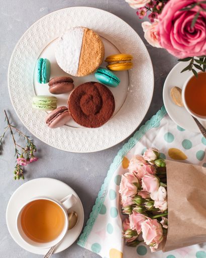 A top view of tasty sweets on the table served with tea and arranged with flowers