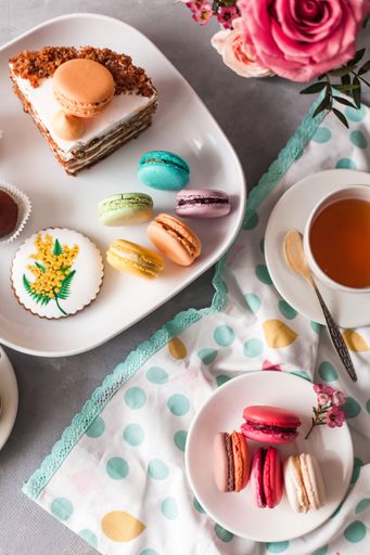 A top view of tasty sweets on the table served with tea and arranged with flowers