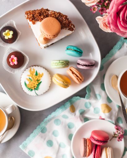 A top view closeup of a chocolate cake with and macaroons on a white plate on the table