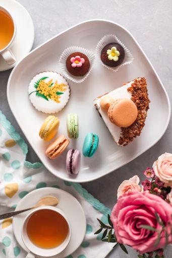 A top view of tasty sweets on the table served with tea and arranged with flowers