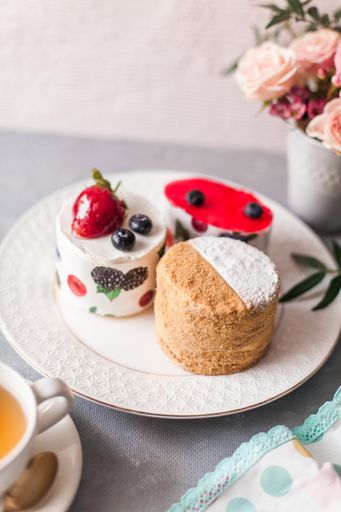 A closeup of tasty sweets on the table served with a tea cup and arranged with flowers