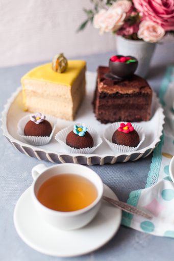 A closeup of tasty sweets on the table served with tea and arranged with flowers