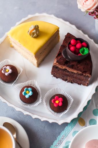 A top view closeup of a variety of cake pieces and macaroons  on the white plate on the grey table