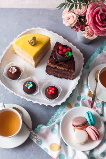 A closeup of tasty sweets on the table served with tea and arranged with flowers