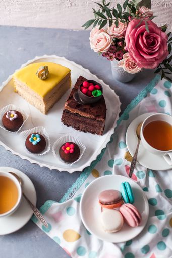 A closeup of tasty sweets on the table served with tea and arranged with flowers