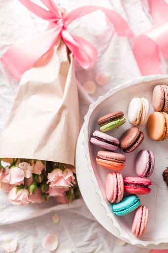 A top view closeup of a variety of colorful macaroons and a bouquet of flowers