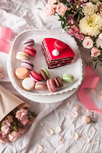 A top view closeup of a variety of cake pieces and macaroons  on the white plate on the grey table