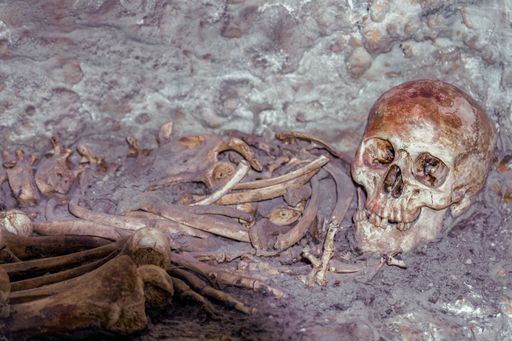 A human skeleton, human remains found in a dark cave.