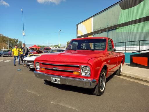 Old red 1967 Chevrolet C10 pickup truck in the street. Colorful industrial background. Classic car show