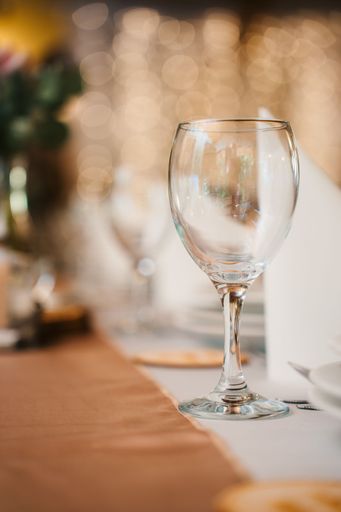 A vertical shot of a wine glass on the table in a restaurant