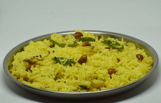 A closeup shot of cooked Lemon rice on a round stainless plate isolated on a white background