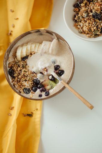 A vertical shot of a  plate coconut plate with a tasty smoothie bowl.