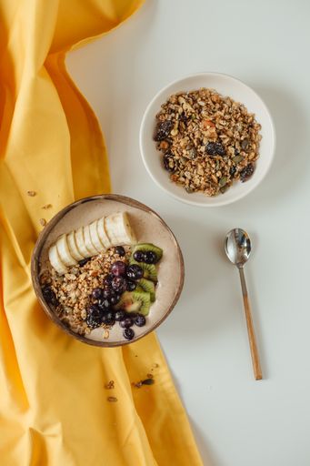 A vertical top-view shot of homemade granola with nuts, raisins, and fruits.