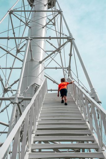 A young boy in bright shirt walking up stairs of unique lighthouse in Port St. Joe, Cape San Blas, historic public landmark