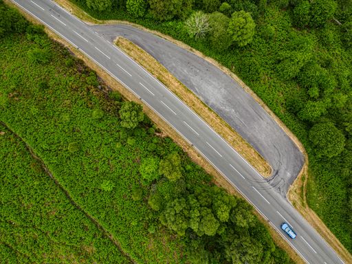 An aerial shot of a road in a forest covered in greenery in the UK