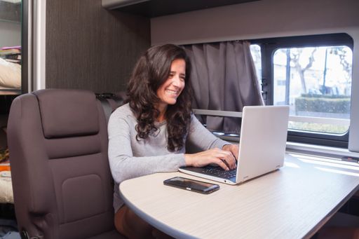 A Spanish woman teleworking and communicating from her mobile office on a vacation at a campsite