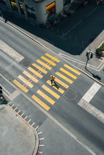 A high angle view of an urban street corner, featuring a car-free crosswalk with a person walking