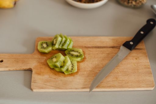 A shot of the sliced juicy kiwi on a wood plate with a knife on the side.