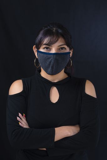 An Ecuadorian woman with a fabric mask posing with crossed hands