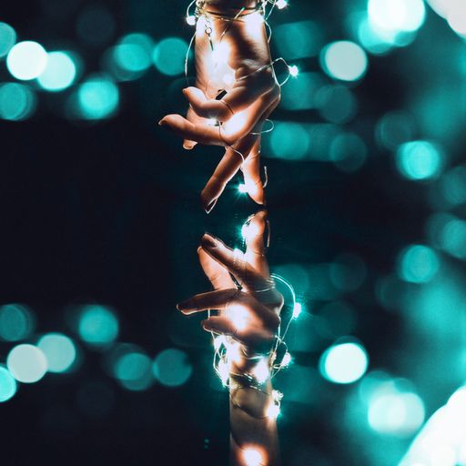 The two hands decorated with lights reaching out to each other.