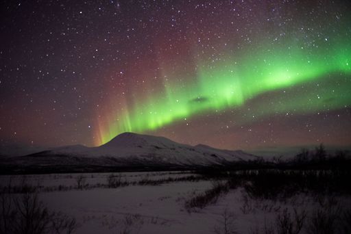 A stunning aurora borealis illuminating the night sky above the rural landscape.