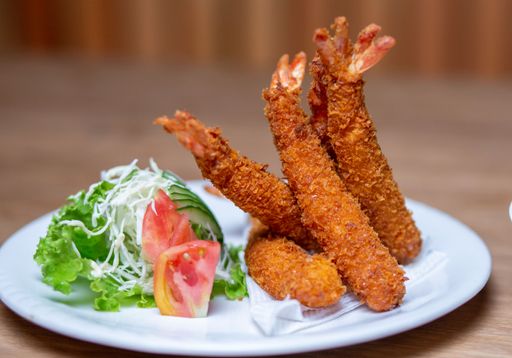 A plate of golden-brown fried chicken strips, served with a side of leafy green salad and a small bowl of creamy dipping sauce