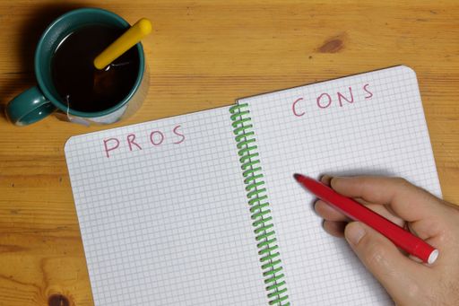A top view of a notebook for determining pros and cons with a cup of tea