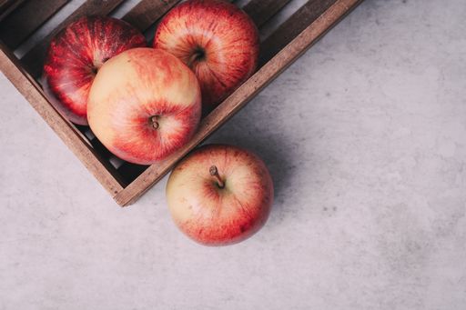 The red apples in a crate on a concrete worktop or work surface with copy space for a magazine