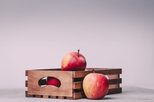 The red apples in a small crate with copy space against a grey pplain background