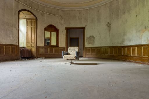 Old armchair in an old dilapidated oval room.