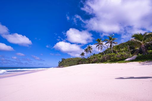 A stunning beachscape of Mahe Island in Seychelles featuring a pristine white sandy beach and lush tropical vegetation in the background