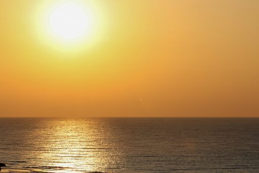 A beautiful view of the sun setting on the horizon line over the peaceful sea
