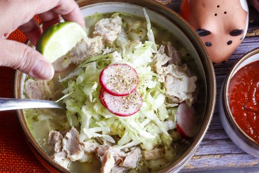 A closeup shot of delicious traditional Mexican white pozole bowl  with lime and radish