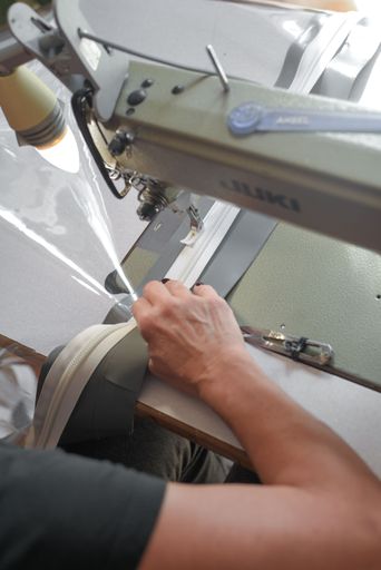 A closeup of a woman carefully  sewing a piece of fabric on a sewing machine