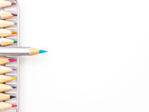 A vibrant array of colored pencils in a metal tin container against a white background